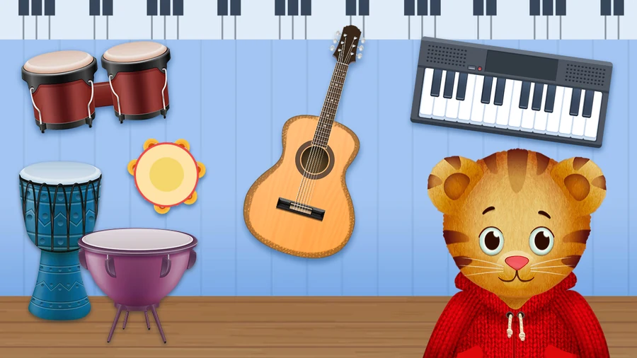 The instrument wall: bongos, a djembe, a timpani and a tambourine on the left, an acoustic guitar in the middle and an electric keyboard on the right, hung on blue panelling above a wooden floor, with Daniel Tiger in his red hoodie looking on from the corner