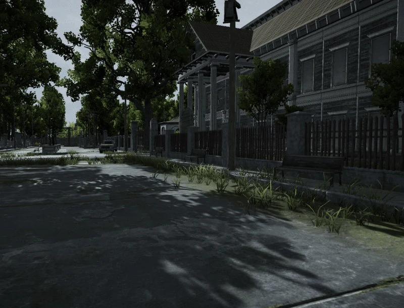 An empty street running past a colonnaded building, a bell mounted on a post at the kerb, railings and benches along the front, weeds pushing through the tarmac